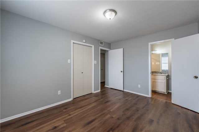 unfurnished bedroom with dark hardwood / wood-style flooring, ensuite bath, and a closet