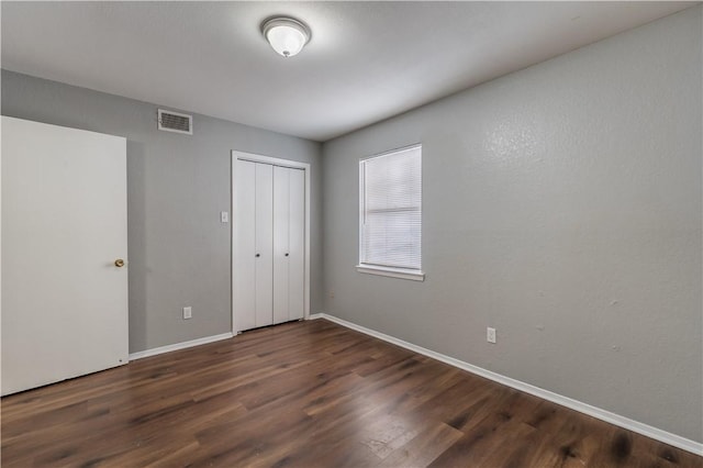 unfurnished bedroom featuring dark wood-type flooring and a closet