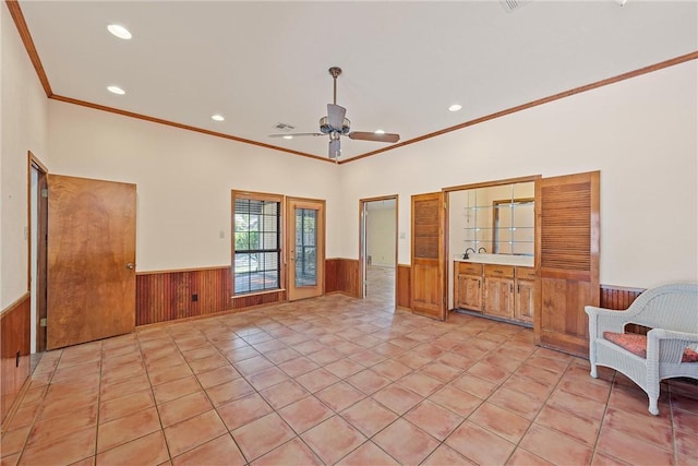 unfurnished living room with wood walls, ceiling fan, light tile patterned flooring, and ornamental molding