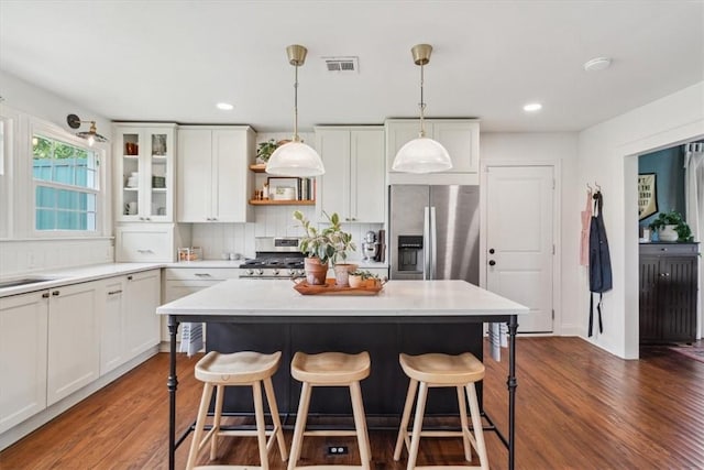 kitchen with white cabinets, decorative light fixtures, stainless steel appliances, and dark wood-type flooring