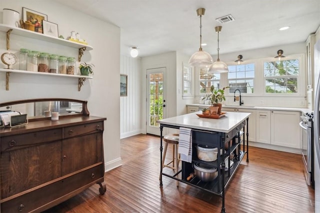 kitchen featuring white cabinetry, sink, dark wood-type flooring, decorative light fixtures, and a kitchen island