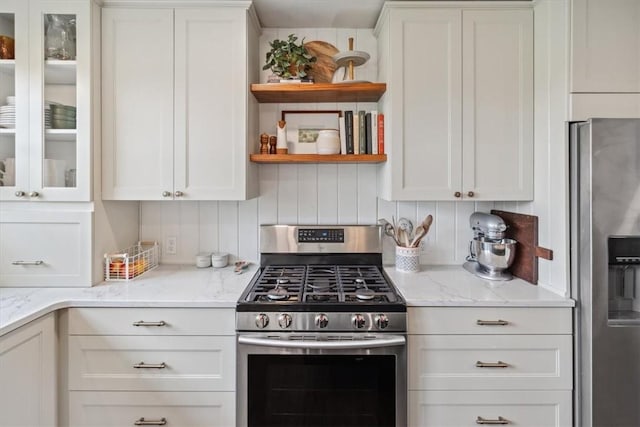 kitchen with backsplash, light stone countertops, white cabinets, and appliances with stainless steel finishes