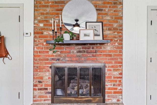 interior details featuring ceiling fan and a brick fireplace