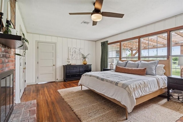 bedroom featuring dark hardwood / wood-style flooring, a brick fireplace, ceiling fan, and crown molding