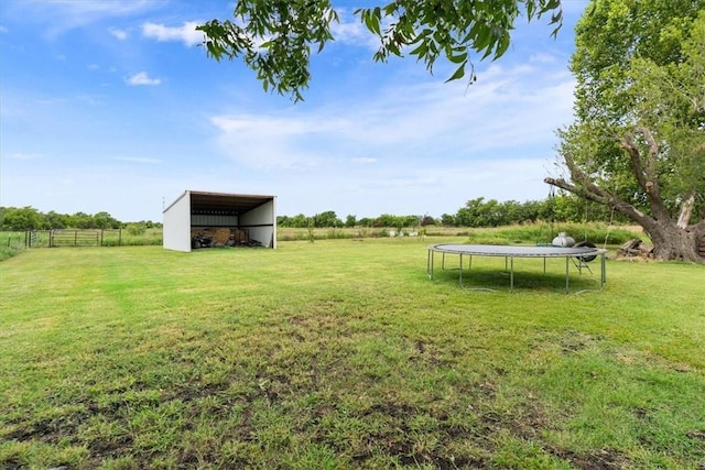 view of yard featuring a rural view, a trampoline, and an outbuilding