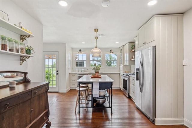 kitchen with appliances with stainless steel finishes, a center island, dark wood-type flooring, and a kitchen breakfast bar