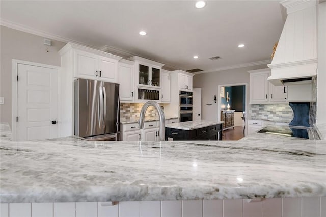 kitchen with white cabinets, appliances with stainless steel finishes, a center island, and decorative backsplash