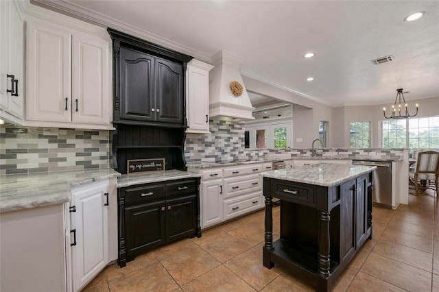 kitchen featuring decorative backsplash, crown molding, light tile patterned floors, a chandelier, and a center island