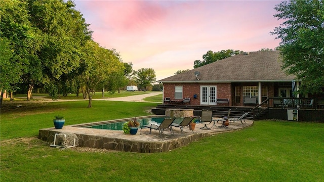 back house at dusk with a yard, a patio, and french doors