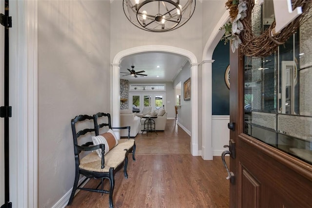 entrance foyer featuring french doors, ceiling fan with notable chandelier, dark hardwood / wood-style floors, ornamental molding, and decorative columns