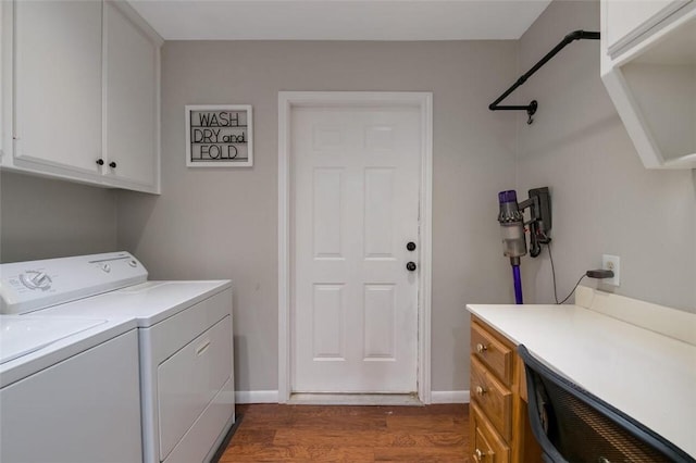 clothes washing area with separate washer and dryer, dark wood-type flooring, and cabinets