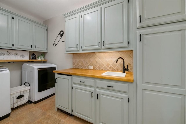 clothes washing area featuring cabinets, washing machine and dryer, light tile patterned flooring, and sink