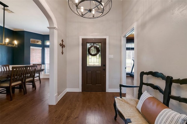 foyer featuring ornamental molding, dark hardwood / wood-style flooring, an inviting chandelier, and a healthy amount of sunlight