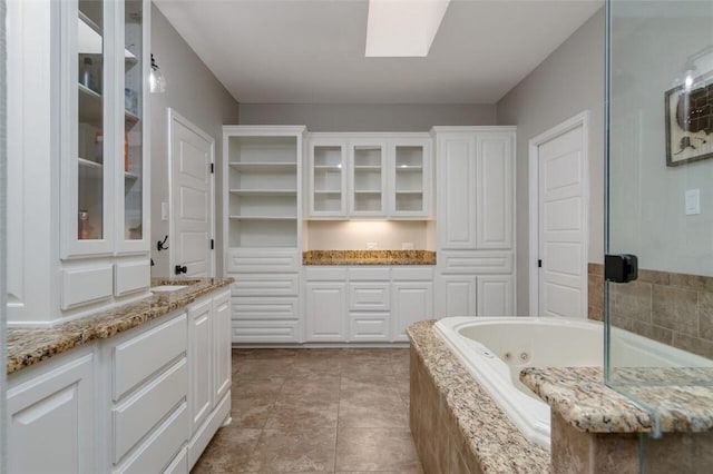 bathroom with vanity, a relaxing tiled tub, and tile patterned floors