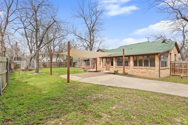 rear view of house featuring a lawn, a fenced backyard, brick siding, and a patio area