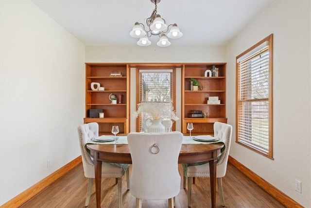 dining area featuring a notable chandelier, baseboards, and wood finished floors