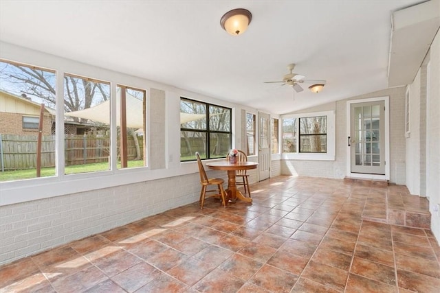 unfurnished sunroom featuring plenty of natural light, a ceiling fan, and vaulted ceiling