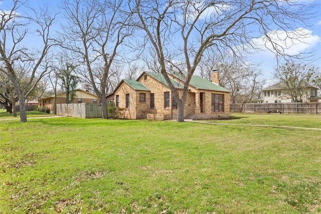 exterior space with a lawn, a chimney, and fence