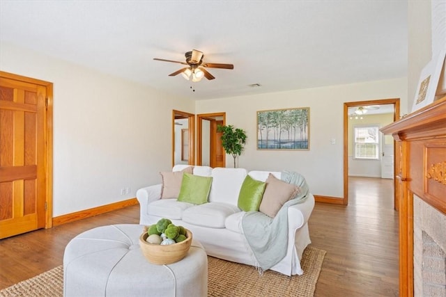 living room featuring visible vents, baseboards, wood finished floors, and a ceiling fan