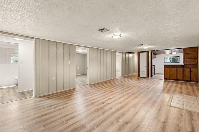 unfurnished living room featuring light hardwood / wood-style floors and a textured ceiling