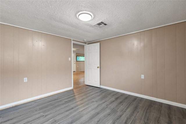 spare room featuring hardwood / wood-style flooring and wood walls