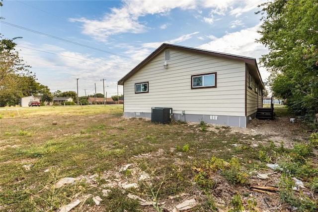 view of side of home with central AC unit and a lawn