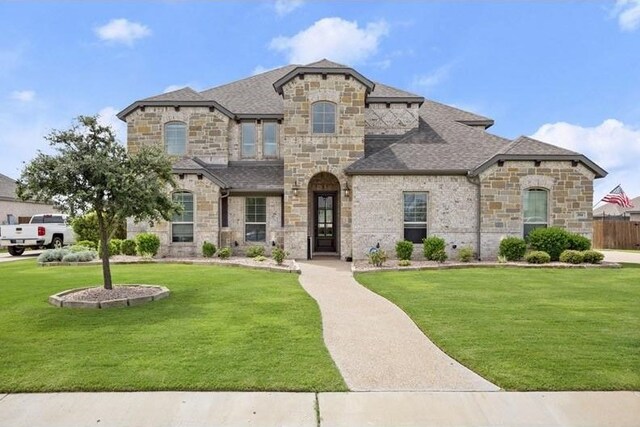 french country style house featuring roof with shingles and a front yard