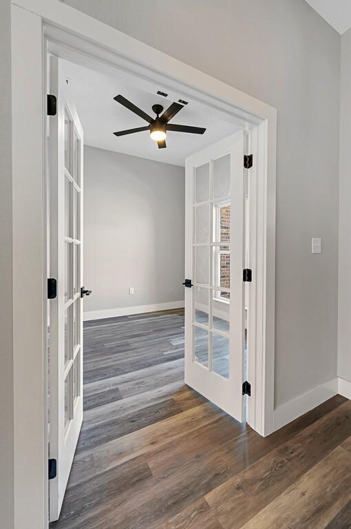 unfurnished room with french doors, ceiling fan, and dark wood-type flooring