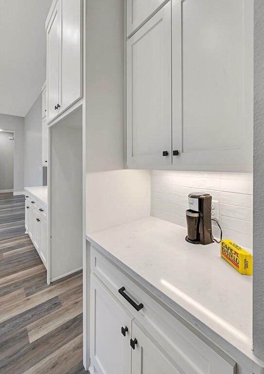 kitchen featuring backsplash, white cabinets, and hardwood / wood-style flooring