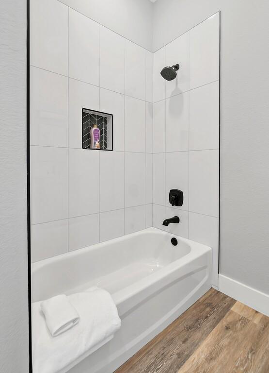 bathroom featuring tiled shower / bath combo and hardwood / wood-style flooring