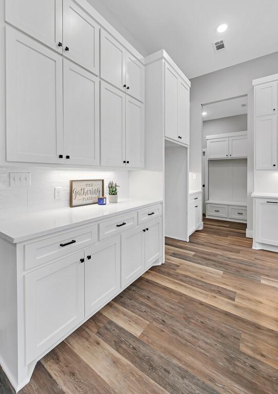 kitchen with tasteful backsplash, white cabinetry, and dark wood-type flooring