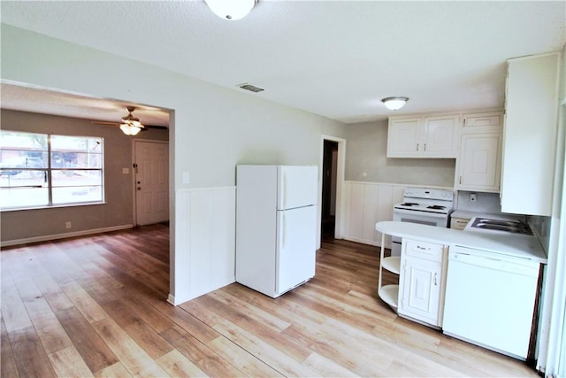 kitchen featuring white cabinetry, sink, light hardwood / wood-style floors, and white appliances