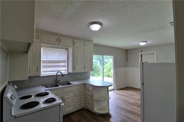 kitchen with white appliances, sink, light hardwood / wood-style flooring, white cabinetry, and kitchen peninsula