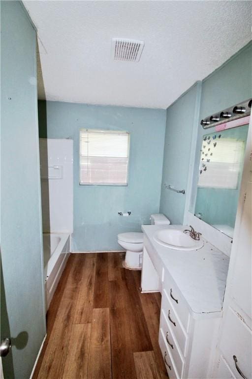 full bathroom featuring hardwood / wood-style floors, vanity, tub / shower combination, and toilet