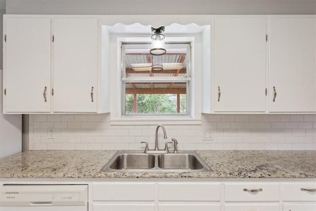 kitchen with white dishwasher, white cabinetry, and sink