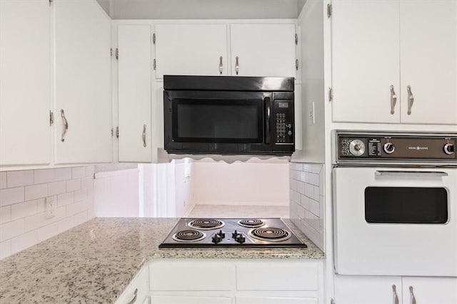 kitchen with black appliances, light stone counters, white cabinetry, and tasteful backsplash