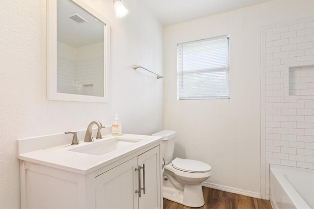 full bathroom featuring tiled shower / bath, vanity, wood-type flooring, and toilet