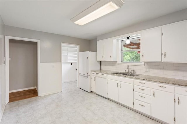 kitchen featuring tasteful backsplash, light stone counters, white appliances, sink, and white cabinets