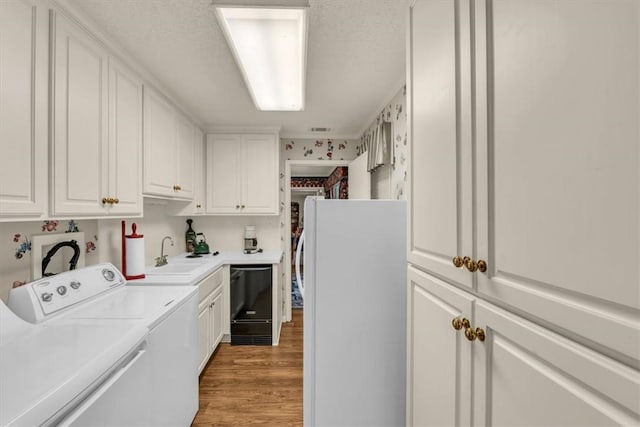 washroom featuring independent washer and dryer, light hardwood / wood-style flooring, and sink