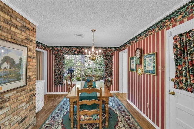 dining space with hardwood / wood-style flooring, ornamental molding, a textured ceiling, and an inviting chandelier