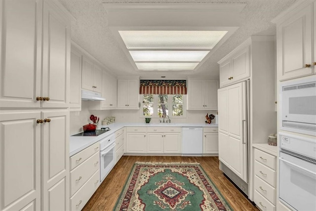 kitchen with a textured ceiling, white cabinetry, dark wood-type flooring, and white appliances