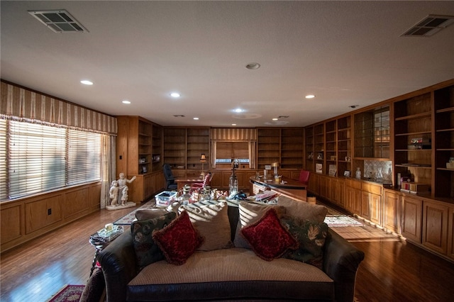 living room with light hardwood / wood-style flooring, built in features, and wood walls