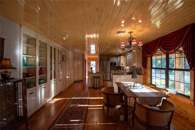 dining space with built in shelves, an inviting chandelier, wooden ceiling, and hardwood / wood-style floors