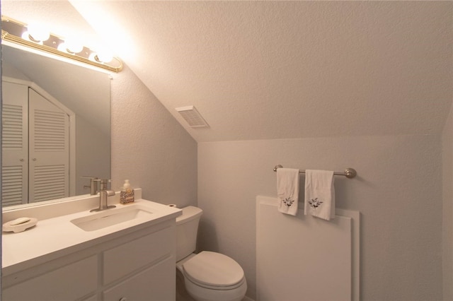 bathroom featuring vanity, lofted ceiling, and toilet