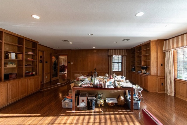 dining space featuring built in shelves, wooden walls, and dark hardwood / wood-style flooring