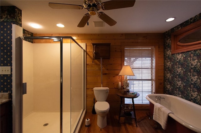 bathroom featuring plus walk in shower, hardwood / wood-style flooring, toilet, and ceiling fan