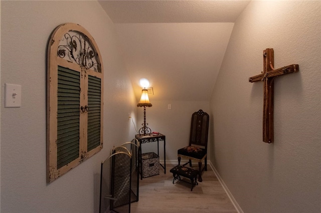 corridor with vaulted ceiling and light wood-type flooring