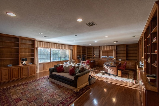 living room with built in shelves, a textured ceiling, and dark hardwood / wood-style floors