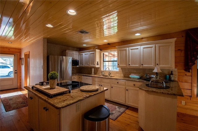 kitchen featuring stainless steel refrigerator, light stone counters, light hardwood / wood-style flooring, and a kitchen island