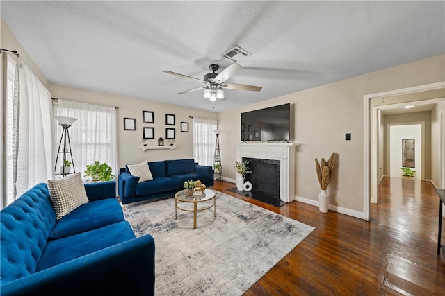 living room featuring a textured ceiling, dark wood-type flooring, and ceiling fan